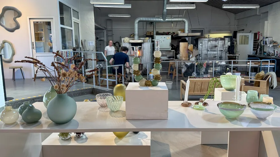 Hand-blown glasses in green and yellow hues in the workshop in Svaneke